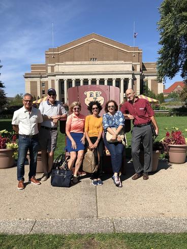 2018 UMAC Fellows standing in front of oversized maroon Goldie Gopher chair in front of the Northrup Building