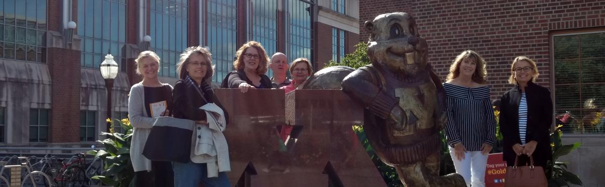 Photograph of 2017 UMAC Fellows standing with statue of Goldy Gopher leaning on large M