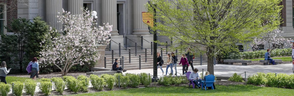 Stock photograph of students walking around in a plant filled area on campus in spring.